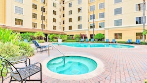 Une cour d’hôtel avec une piscine, des chaises longues et un jacuzzi.
