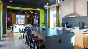 Une cuisine moderne dotée d’un îlot central, de tabourets de bar et d’un coin repas comprenant un canapé et des chaises.
