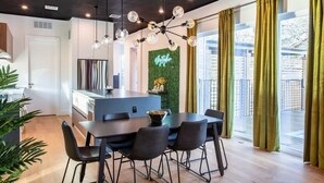 Une cuisine moderne dotée d’un îlot central, d’un coin repas avec une table et des chaises, et d’une grande fenêtre agrémentée de rideaux.