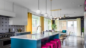 Une cuisine moderne dotée d’un îlot central, de tabourets de bar et de luminaires suspendus.