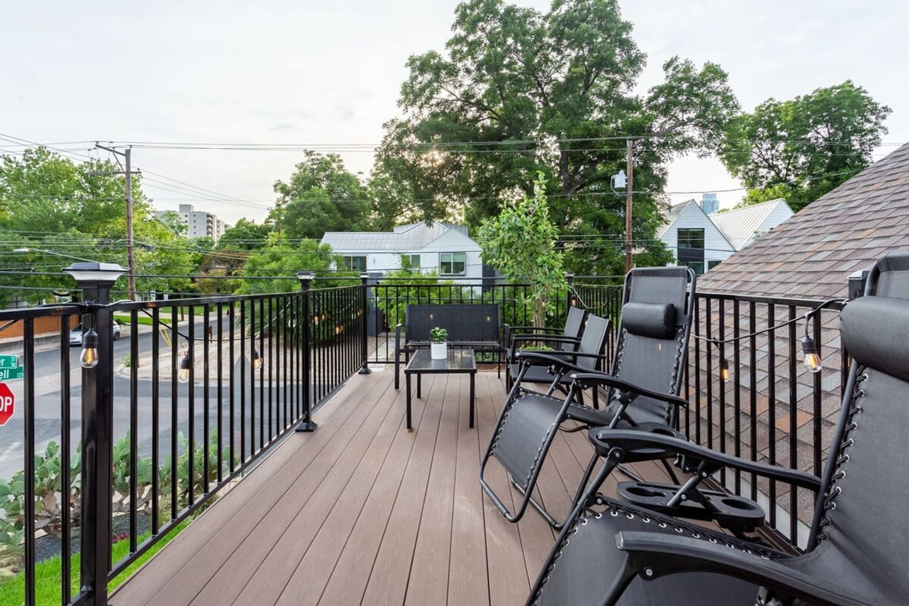 A deck with outdoor furniture and a view of the street.