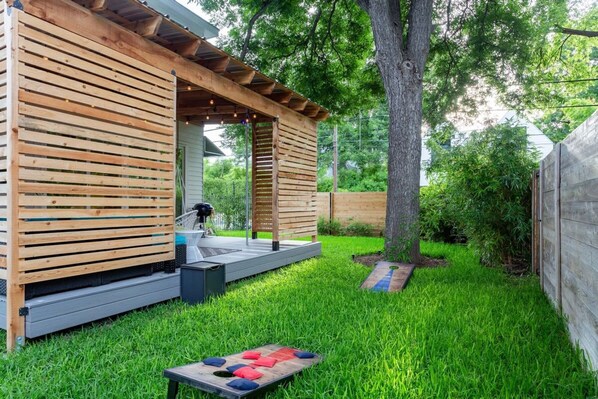 A wooden deck with a pergola, a small outdoor seating area, and a badminton net. - King Kasa 6 Bedroom Walk 6 min to Rainey St (Austin)