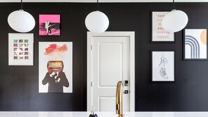 Une salle de bain moderne avec un lavabo blanc, un robinet doré et divers tableaux encadrés accrochés au mur.