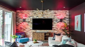 Ein modernes Wohnzimmer mit Backsteinwand, Flachbildfernseher, Sofa, Couchtisch und Bücherregal.