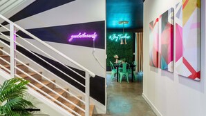 Ein modernes Interieur mit Treppe, Neonreklame und abstrakter Wandkunst.