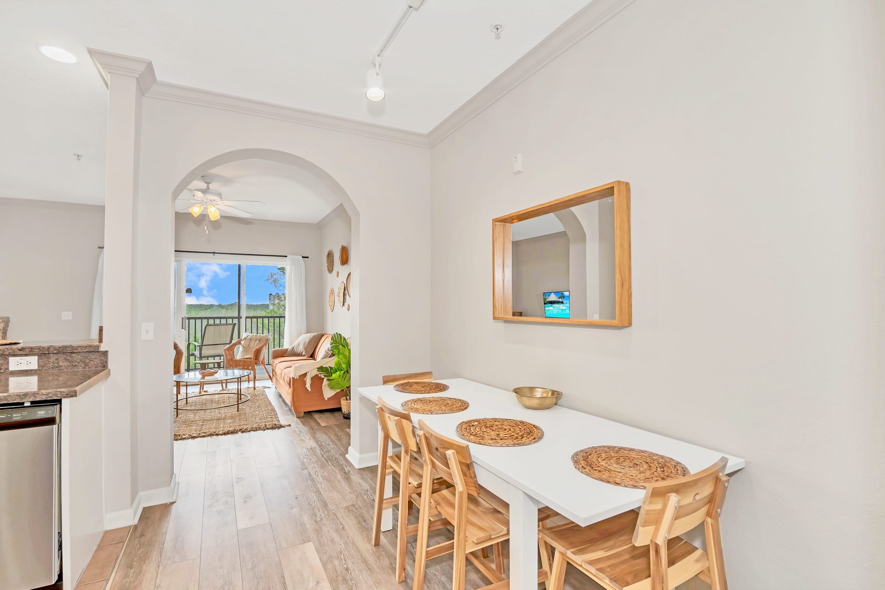 Un comedor moderno con una mesa blanca, sillas de madera y protectores de mesa tejidos.