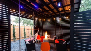 An outdoor patio with a fire pit, seating, and string lights.