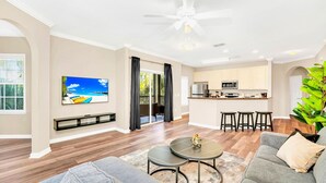 A modern living room with a grey sofa, a coffee table, and a TV mounted on the wall. - Upstay - Modern Family Apartment w Pool Hot Tub (Winter Garden)
