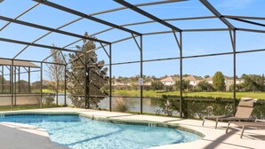 Una piscina techada con vistas a un lago y casas al fondo.