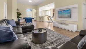 A spacious living room with a pool table, a comfortable sofa, and a television mounted on the wall. - Upstay - New Home Near Disney w Private Pool BBQ (Kissimmee)