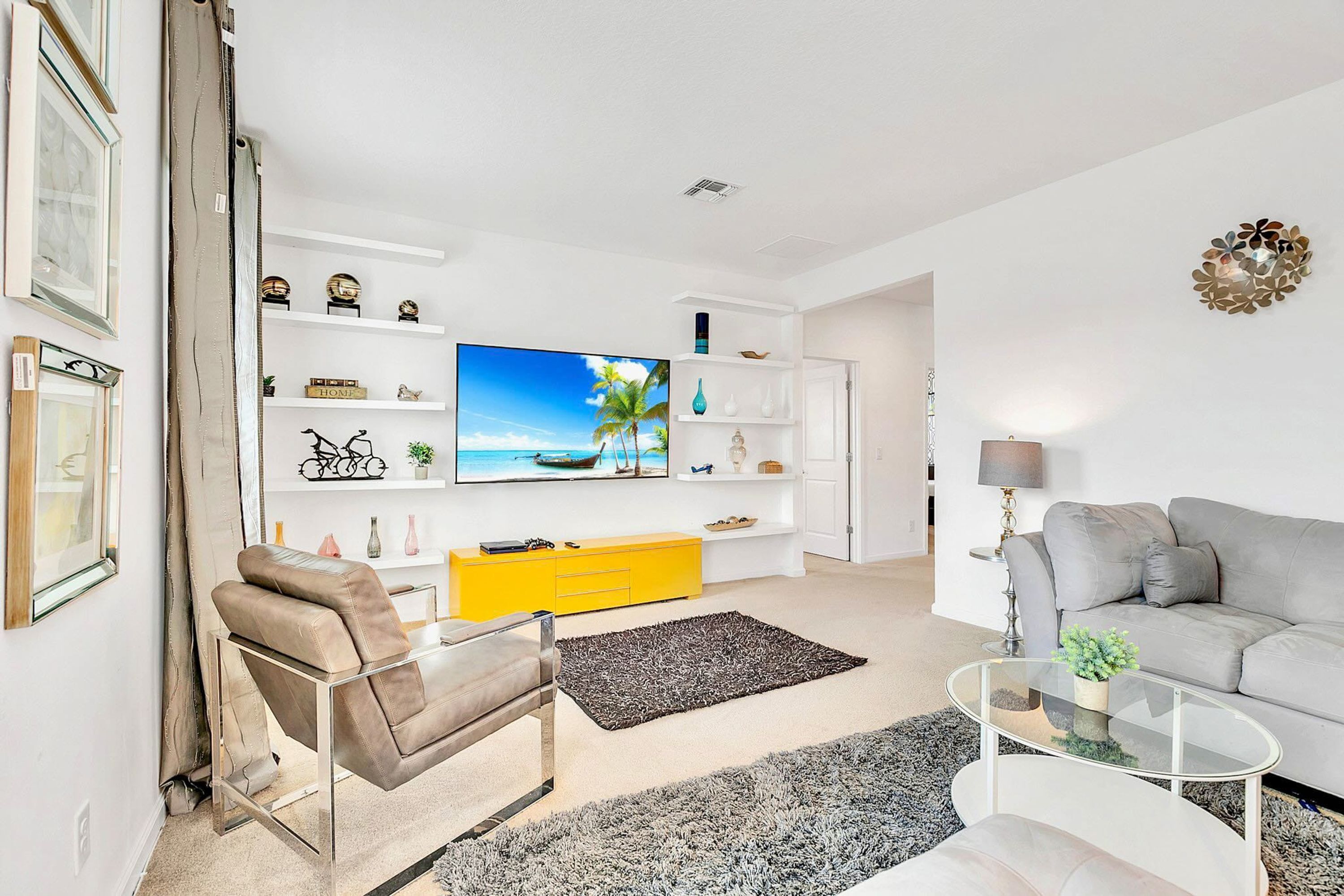 A modern living room with a sofa, a glass coffee table, a TV, and a yellow cabinet.