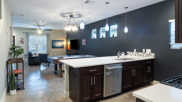 A modern kitchen with a central island, dark cabinetry, and pendant lighting. - Upstay - East Austin Home w Yard Games Fire Pit (Austin)