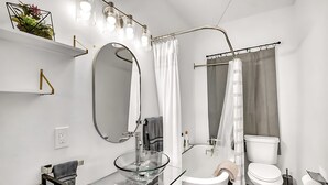 A modern bathroom with a glass sink, white fixtures, a bathtub, and a toilet. - Upstay - Lakeside Getaway - Pool Hot Tub Games (Lakeway)