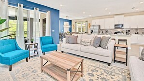 Un salon moderne avec un canapé, deux fauteuils bleus, une table basse en bois et un tapis à motifs.