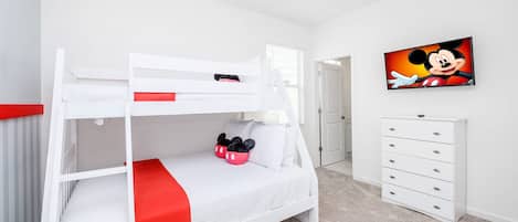 A bunk bed with a red runner, a Mickey Mouse painting, and a white dresser in a bedroom.