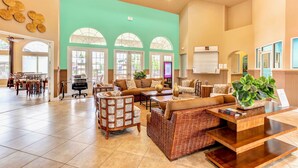 A spacious lobby with a large seating area, a reception desk, and a view of the outdoors through arched windows. - Upstay - Ultimate Orlando Oasis w Pool and Hot Tub (Kissimmee)
