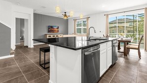 A modern kitchen with a central island, stainless steel appliances, and pendant lighting. - Upstay - Ultimate Orlando Oasis w Pool and Hot Tub (Kissimmee)