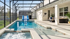 En swimmingpool med ett bubbelbad, omgiven av en täckt uteplats med sittplatser och krukväxter.