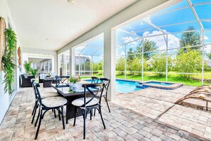 A covered patio with a pool, outdoor furniture, and a view of the surrounding greenery. - Pool Hot Tub Resort Waterslides - Sleeps 16 (Davenport)