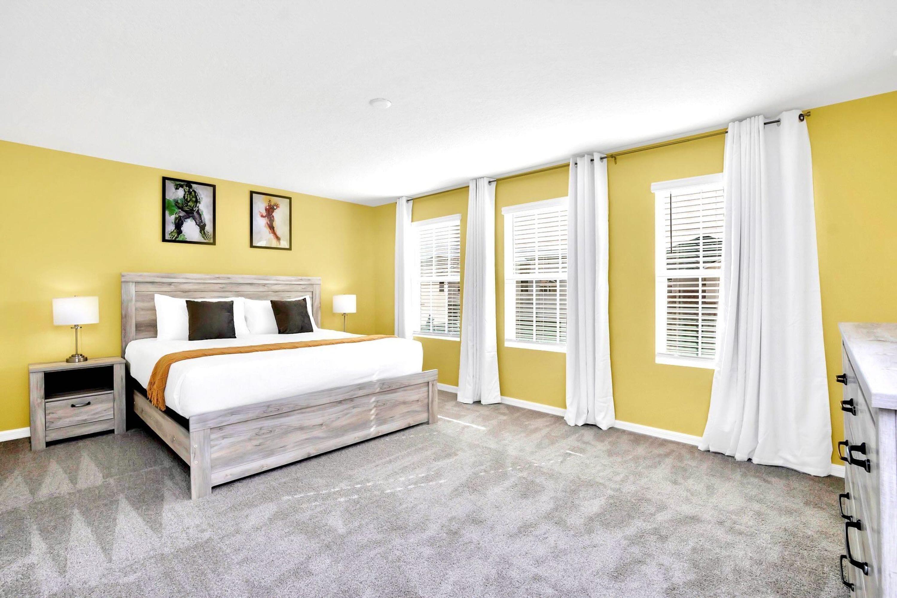 A bedroom with a bed, nightstands, a dresser, and a window with blinds.