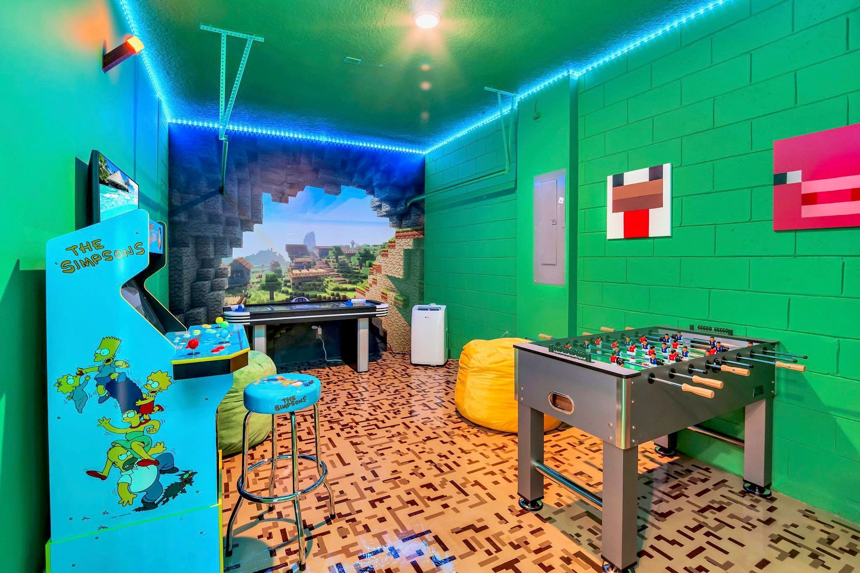 A room with a green wall, a foosball table, a Simpsons-themed foosball table, and a Minecraft-themed wall.