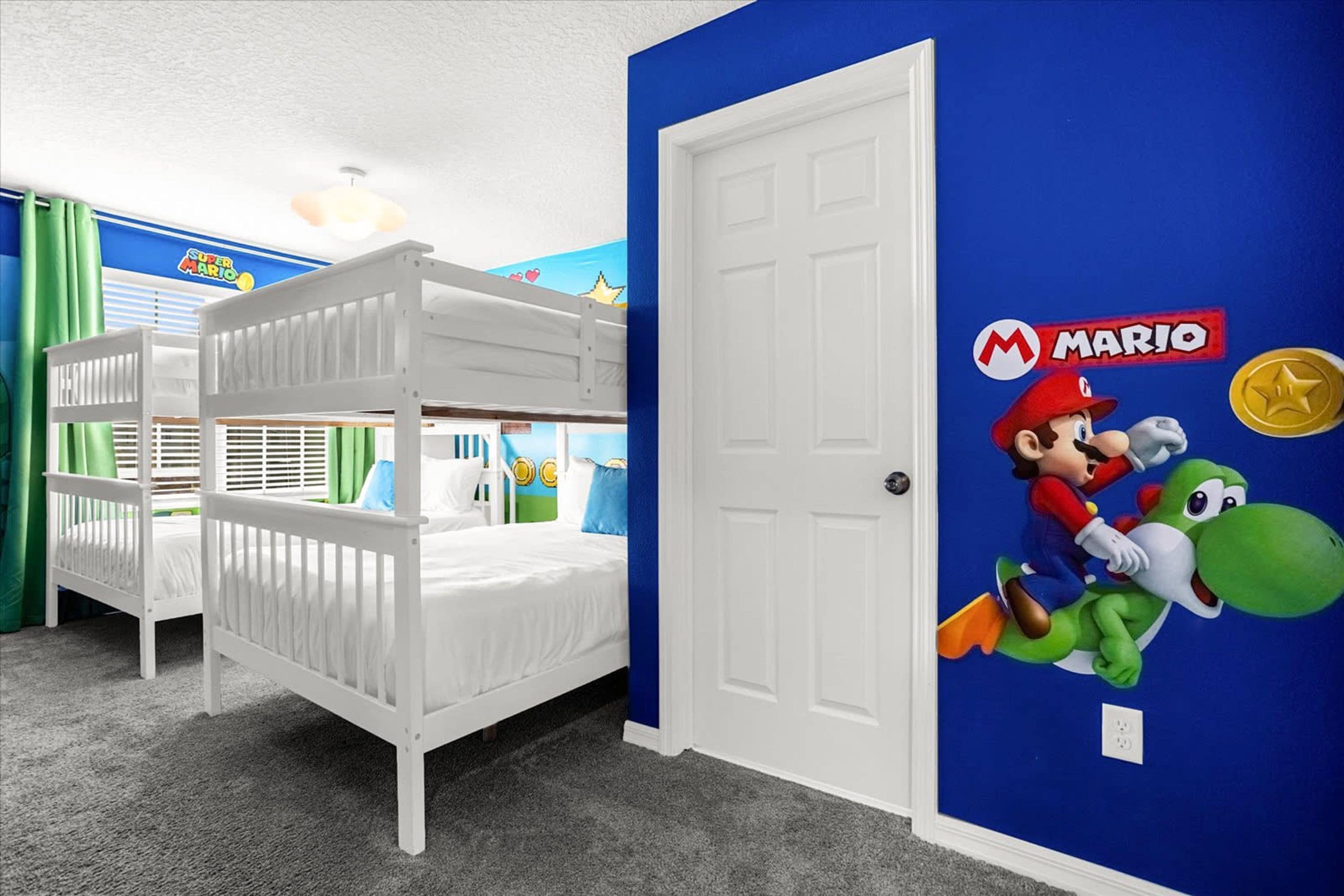 Una stanza con letti a castello, un adesivo decorativo raffigurante Mario e Luigi, e un cartello con Super Mario.