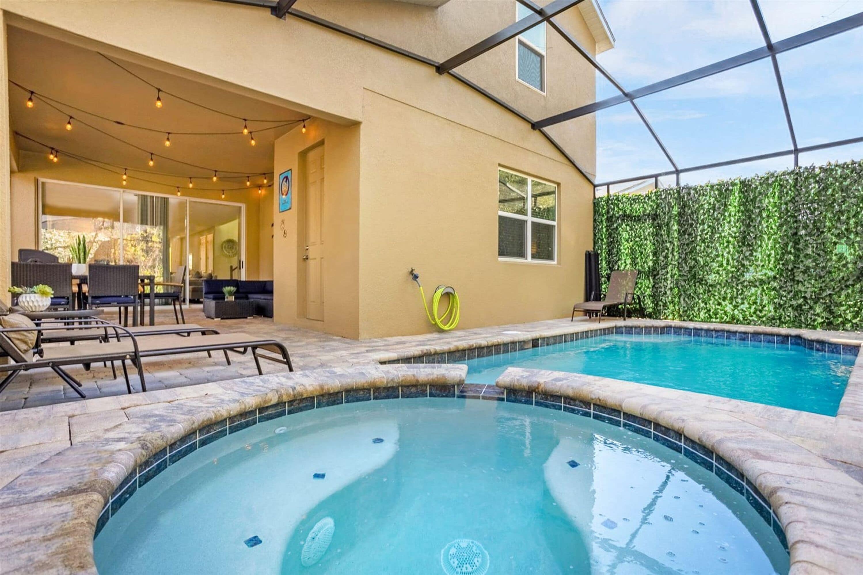 A swimming pool with a hot tub, outdoor seating, and a covered patio area.