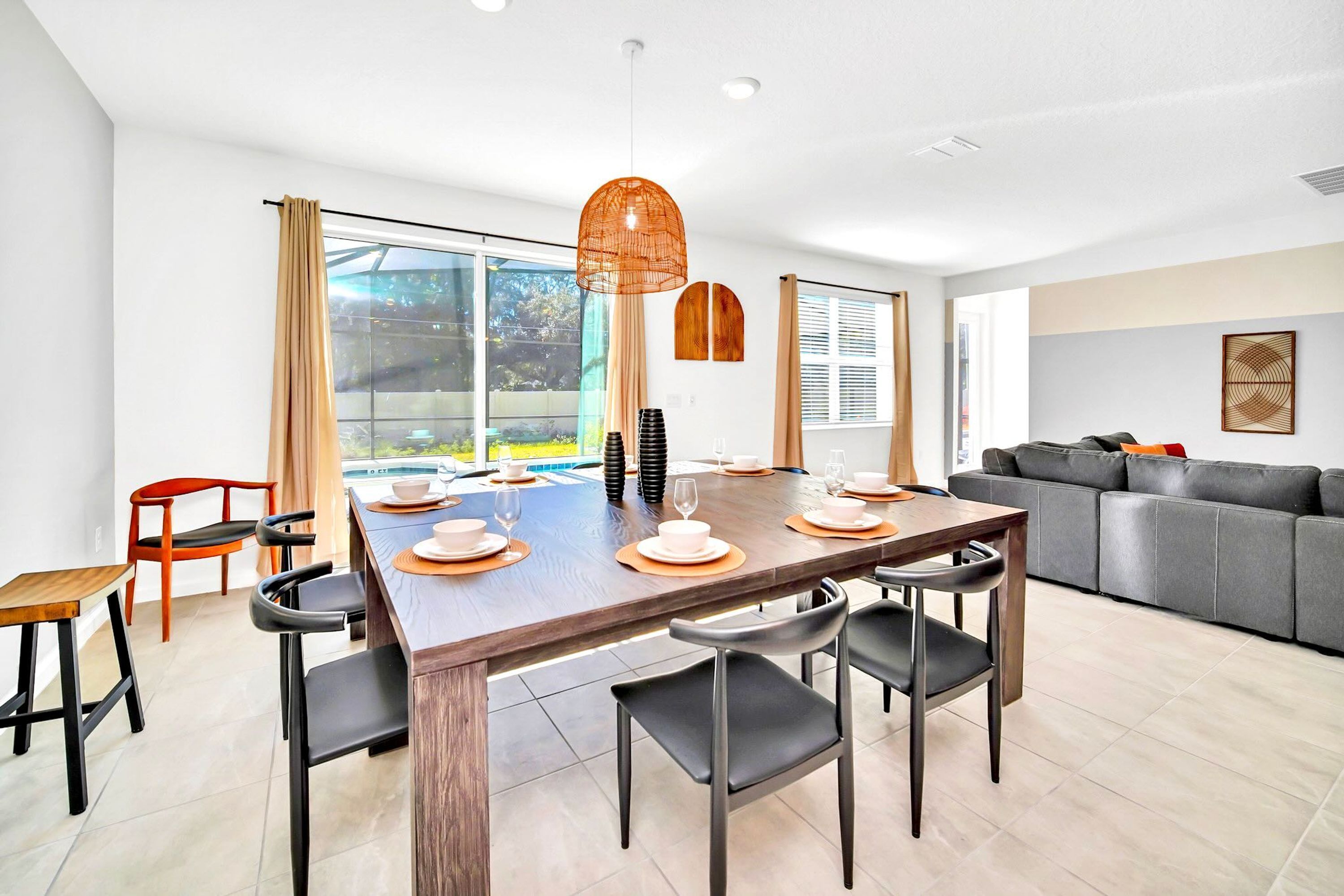 A modern dining area with a wooden table set for four, black chairs, and a large window with curtains.