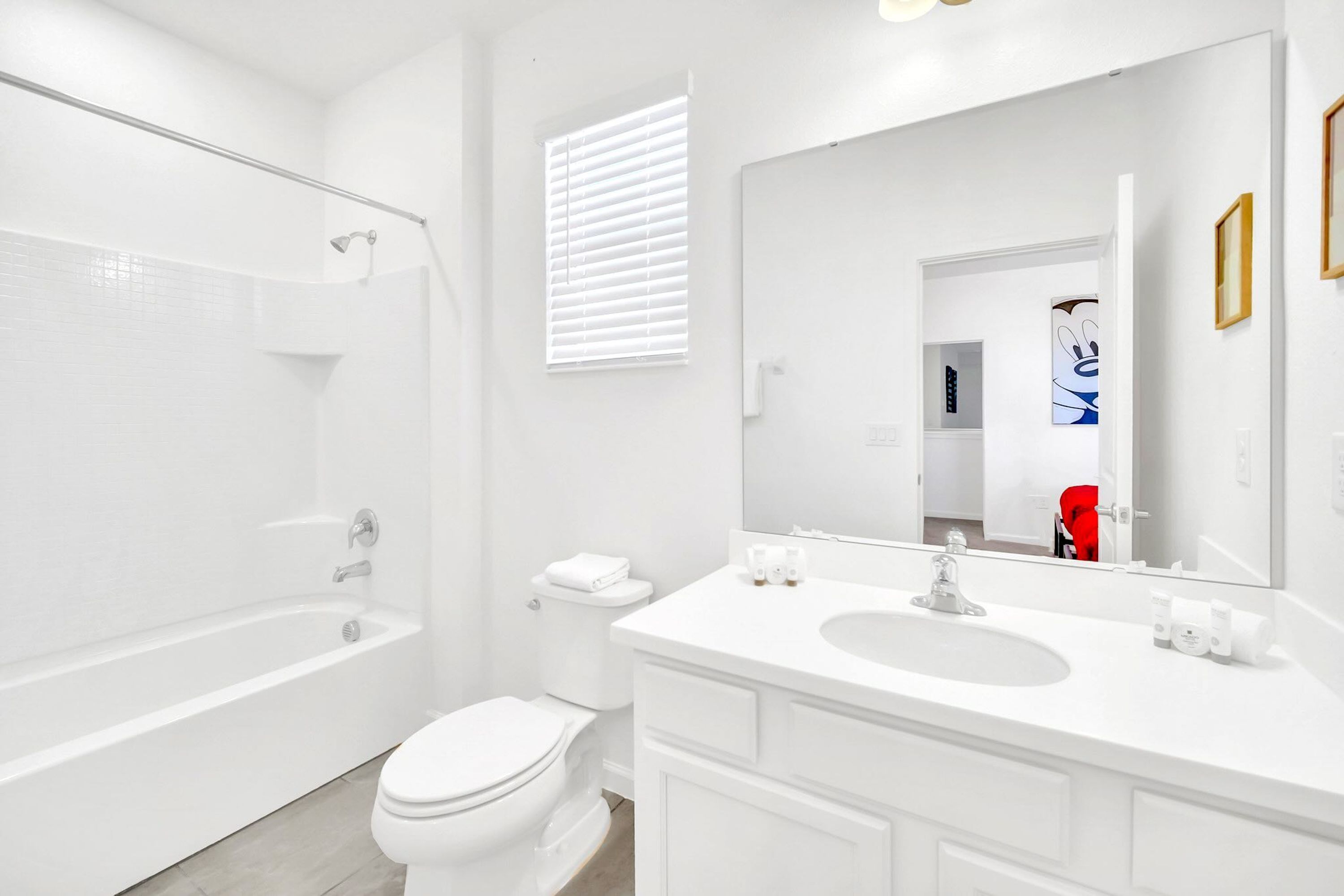 Een moderne badkamer met een bad, toilet en wastafel met een grote spiegel.