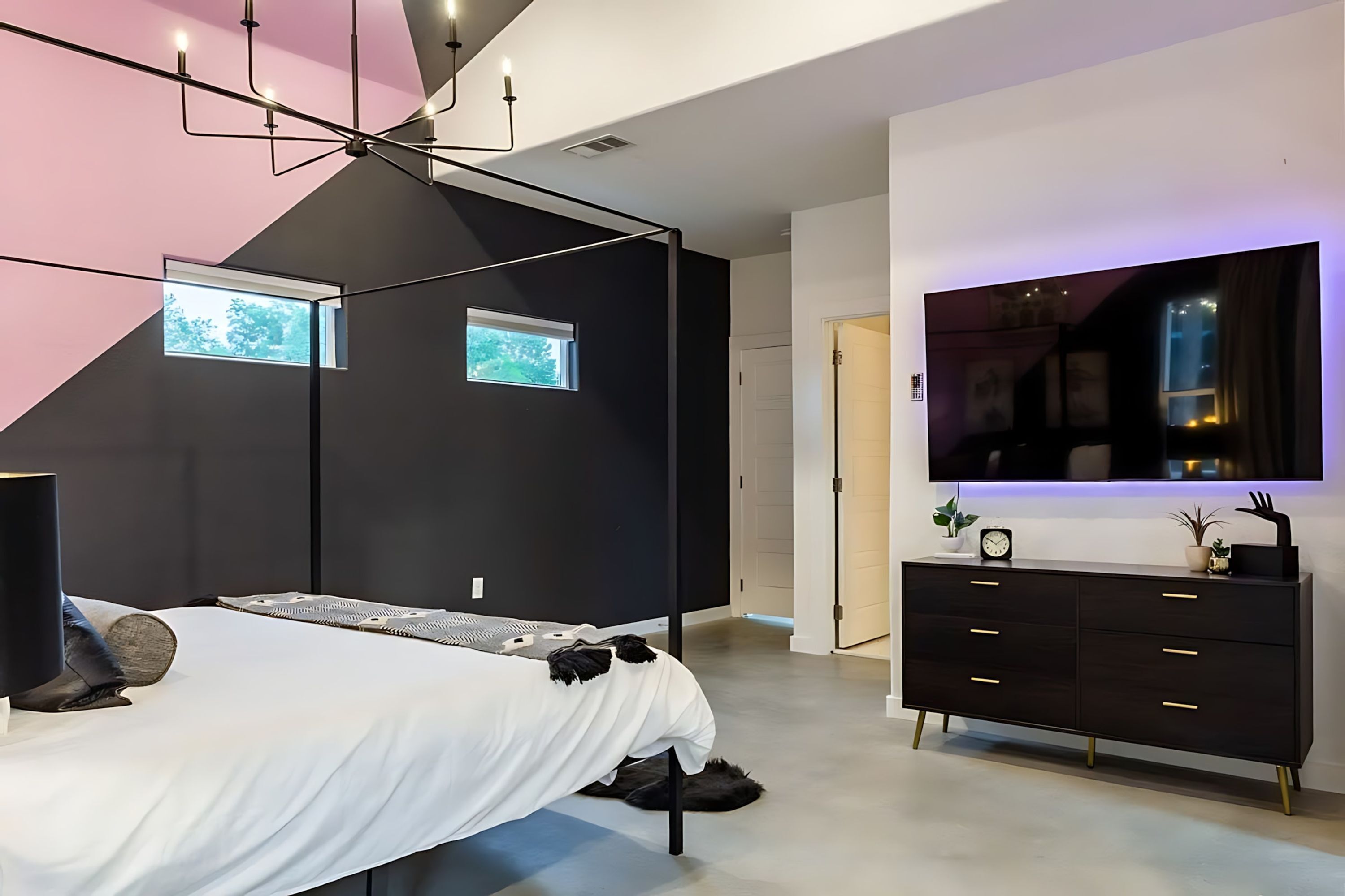 Une chambre à coucher moderne avec un lit, une commode et un téléviseur fixé au mur.