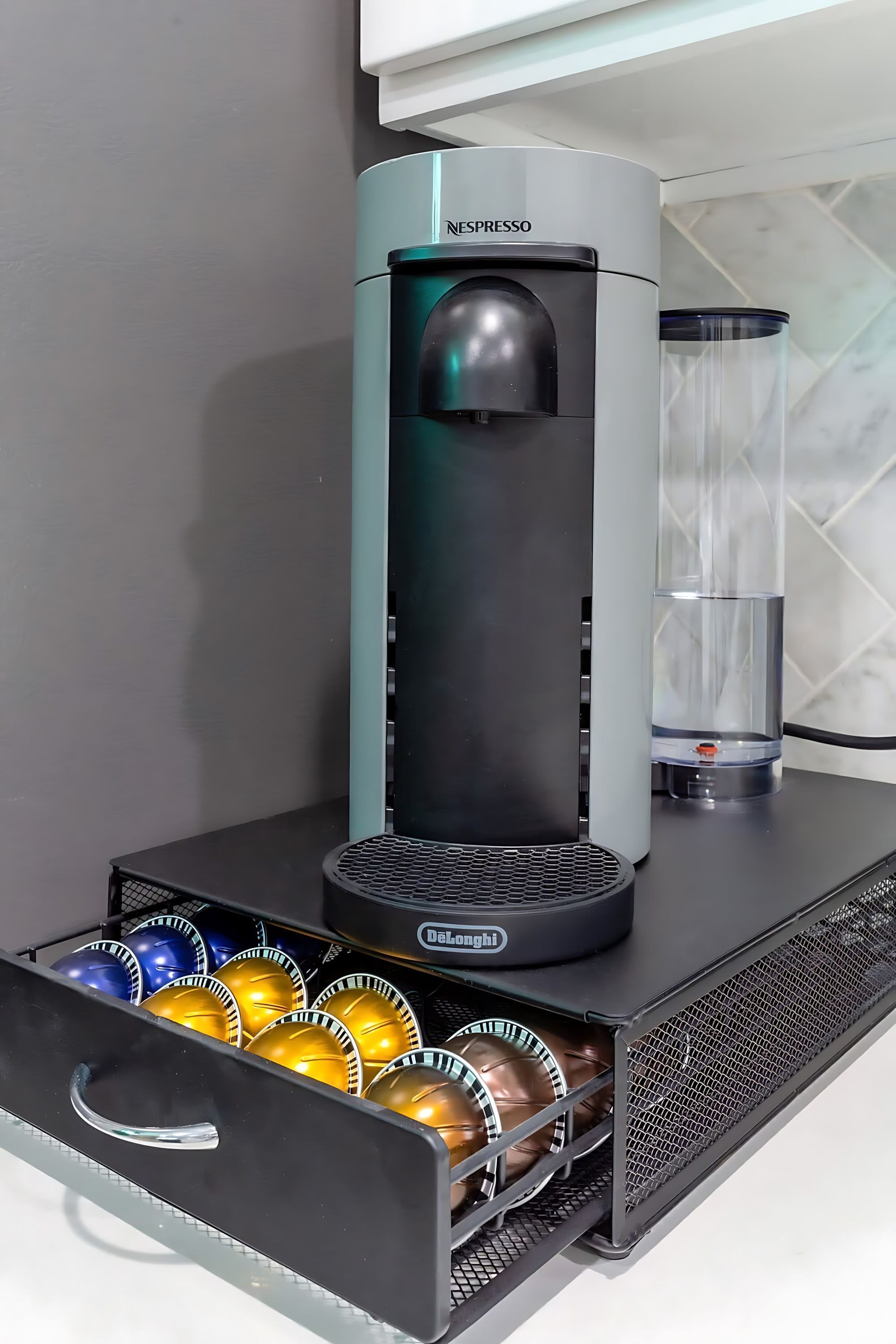 A Nespresso coffee machine with a water reservoir and a drawer containing coffee capsules.