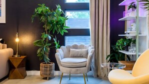 A modern living room with a dark wall, a white armchair, a round table, and a floor lamp. - Pool Hottub Magic School Bus 5 Mins to Downtown (Austin)