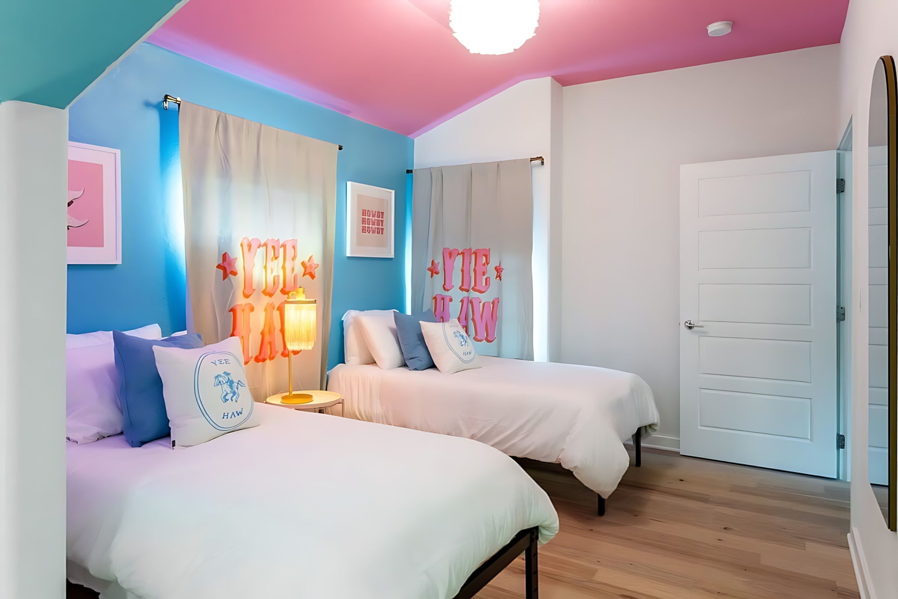 A bedroom with two beds, a ceiling light, and a door.