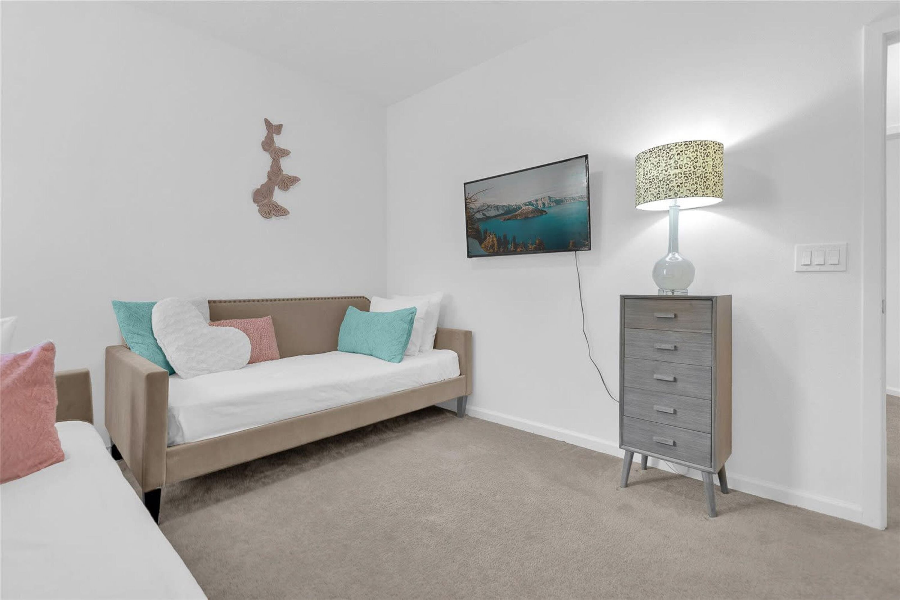 A bedroom with a bed, a dresser, a wall-mounted TV, and a painting.