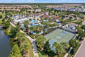 An aerial view of a resort with multiple swimming pools, a basketball court, and surrounding residential buildings. - Spacious 8BR Home for Large Group - Pool Games (Kissimmee)
