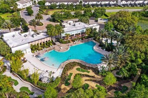 Ein Luftbild eines Resorts mit einem großen Schwimmbecken, umgeben von Palmen und einem Golfplatz.