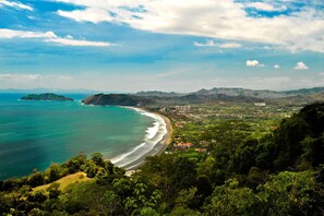 A coastal town with a beach, surrounded by hills and greenery. - Upstay - Brand New Condo w Pool - 5 Mins to Beach (Jacó)