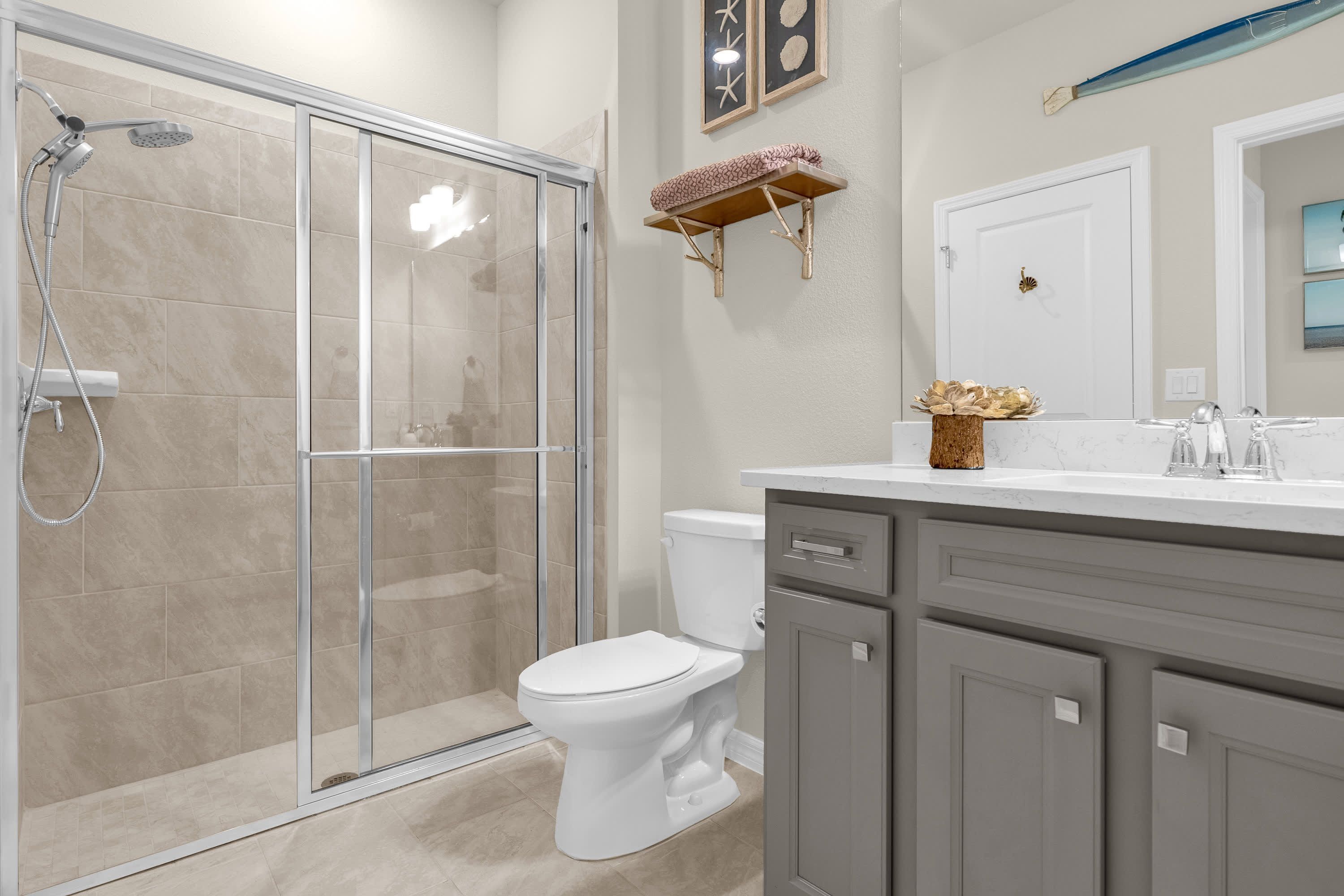 Une salle de bain avec une douche à parois de verre, des toilettes et un meuble-lavabo avec un miroir.