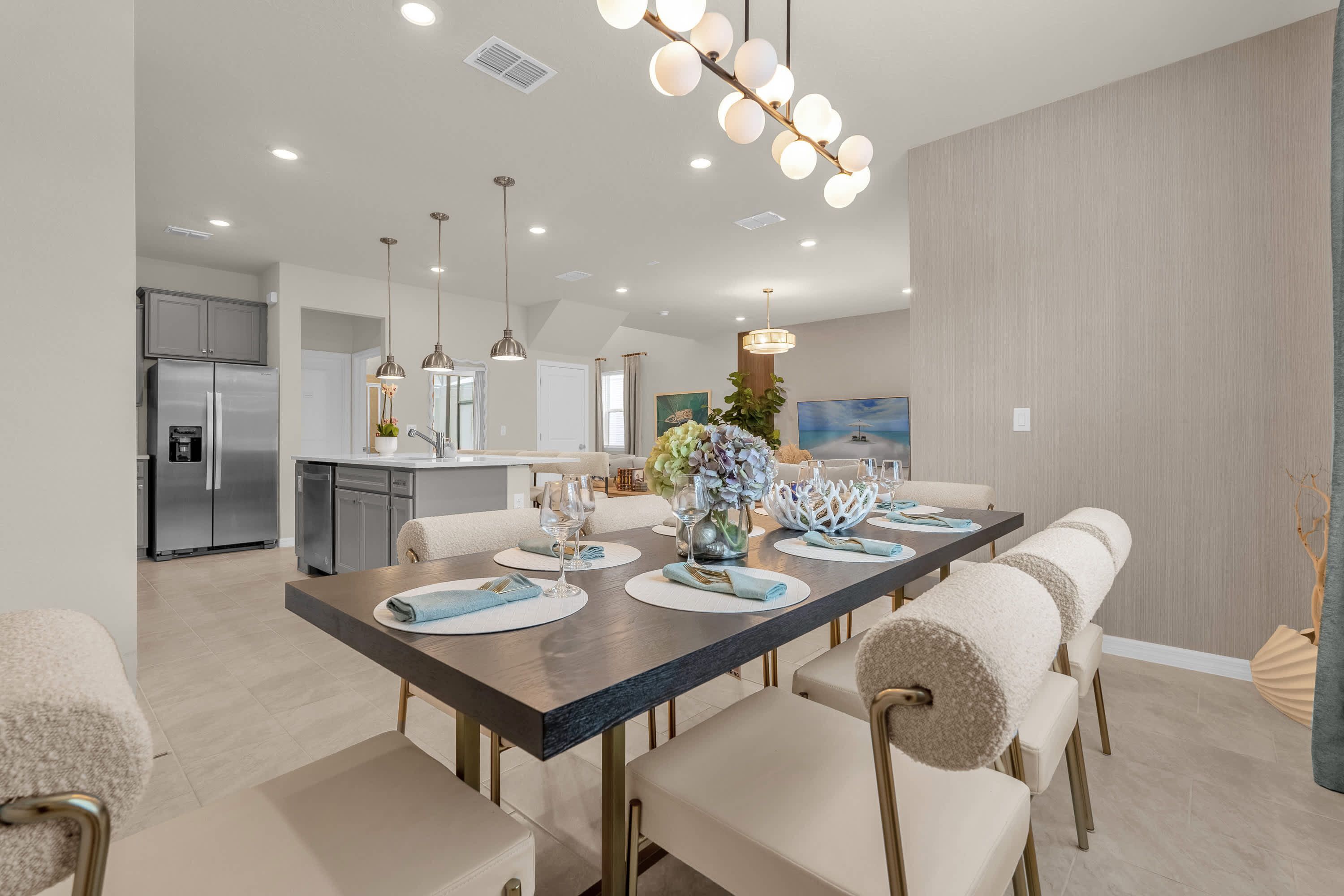 Un espace repas moderne avec une longue table, des chaises et une cuisine en arrière-plan.
