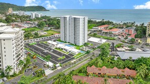 Ein Hochhaus-Hotel mit mehreren Etagen, einem Parkplatz und Blick aufs Meer.