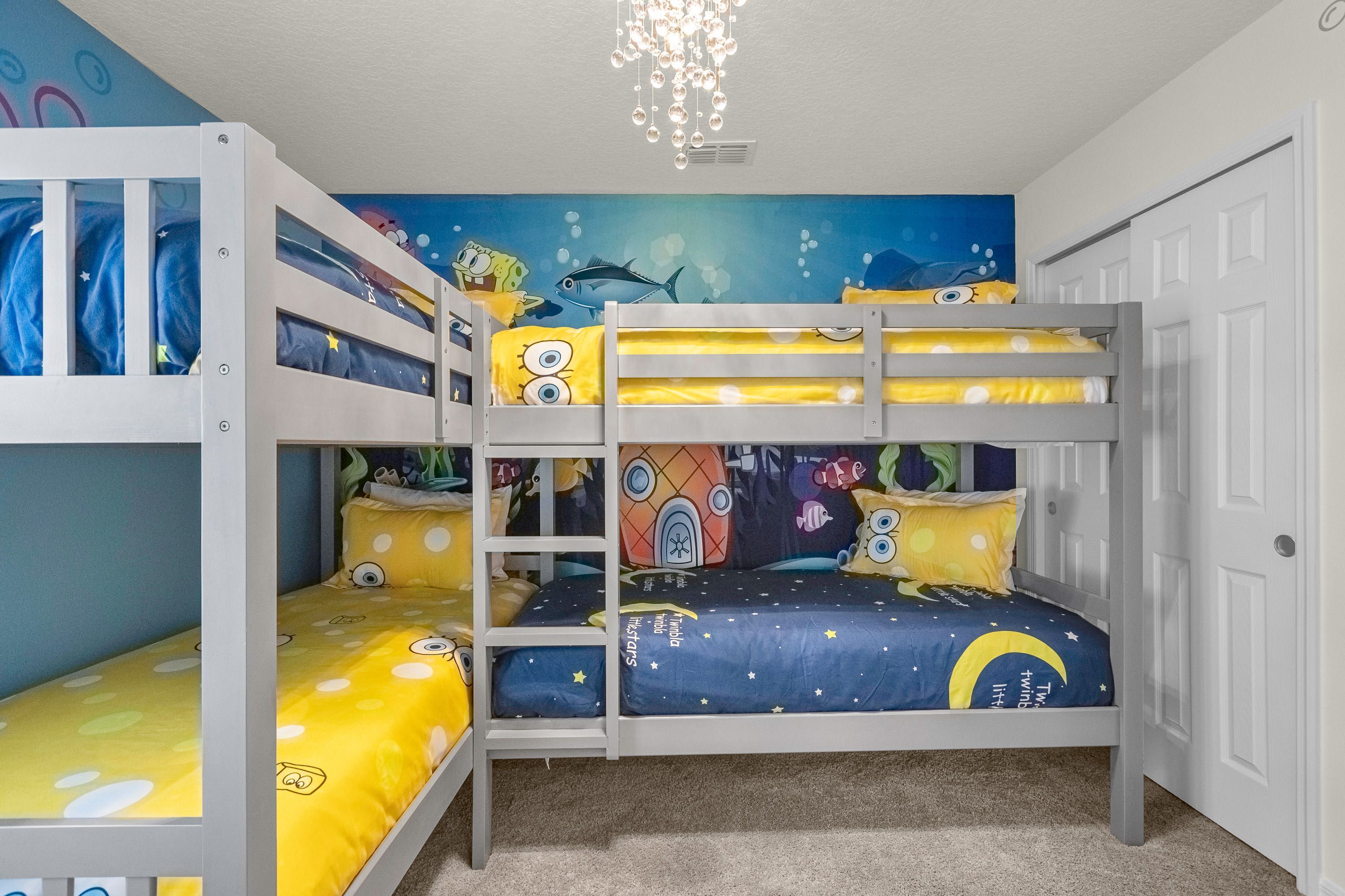 A bunk bed room with a mural of an underwater scene, a chandelier, and a door.