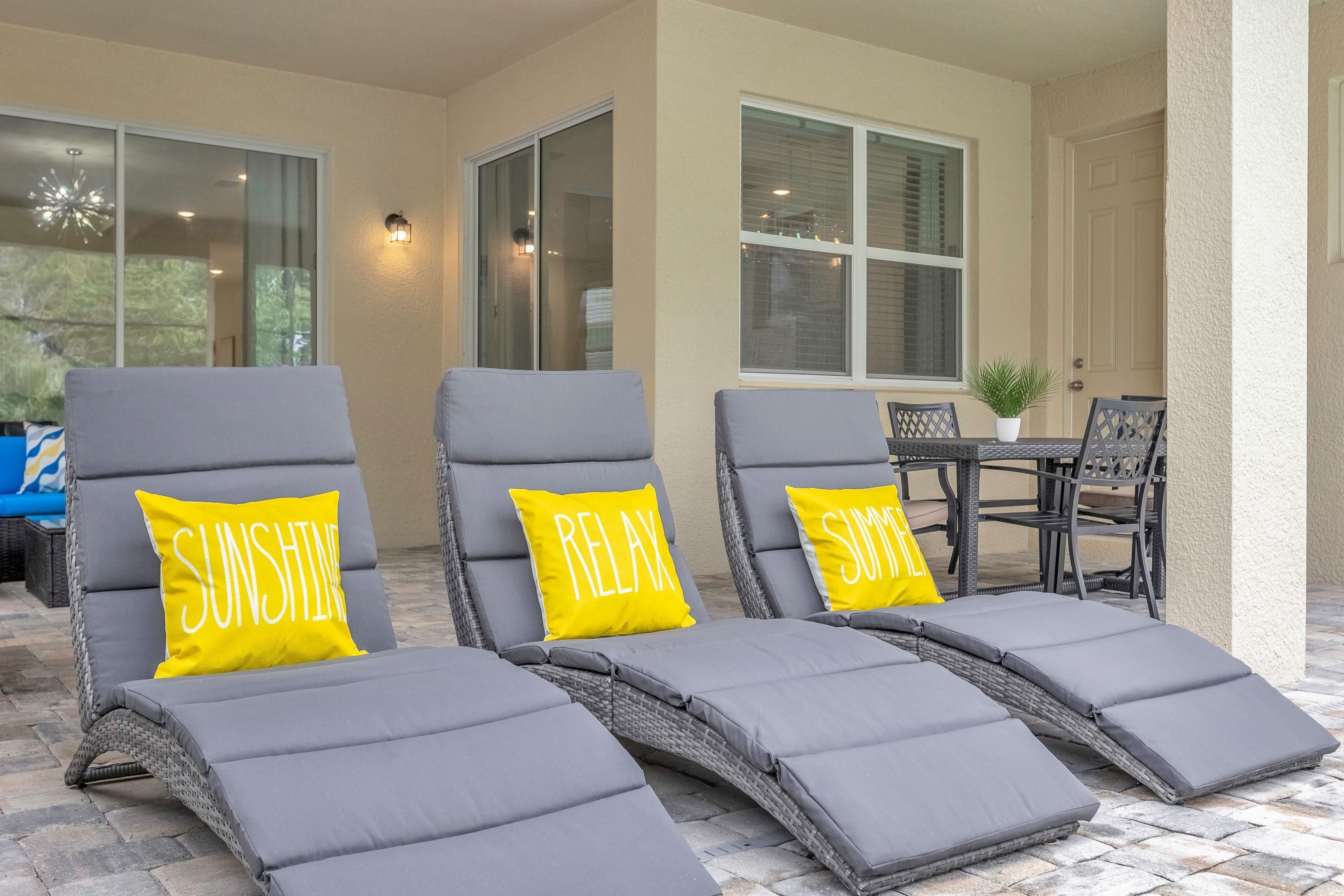 Three grey lounge chairs with yellow cushions, one of which has the word "RELAX" on it.