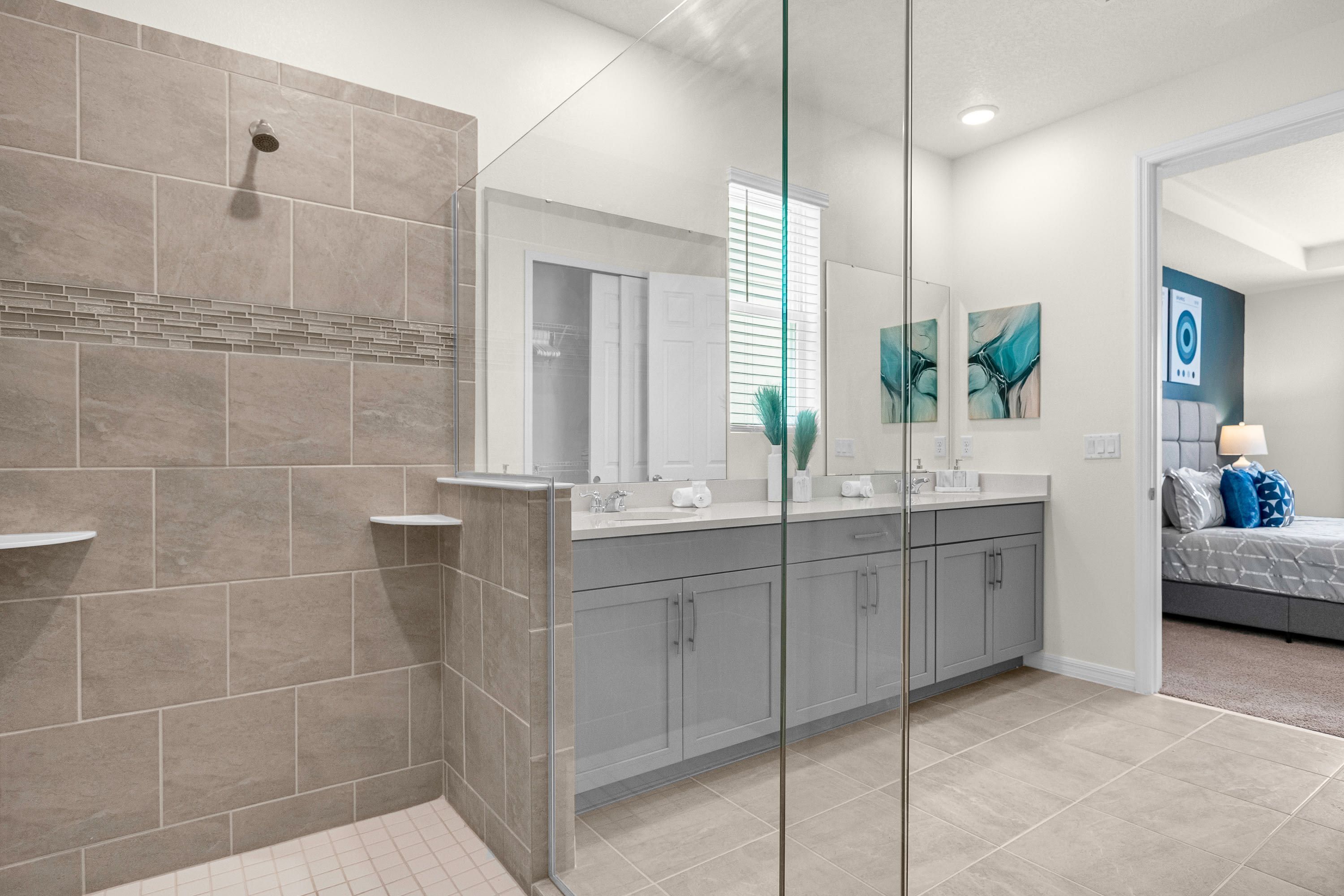A modern bathroom with a glass shower enclosure, a large mirror, and a vanity with a sink and countertop.