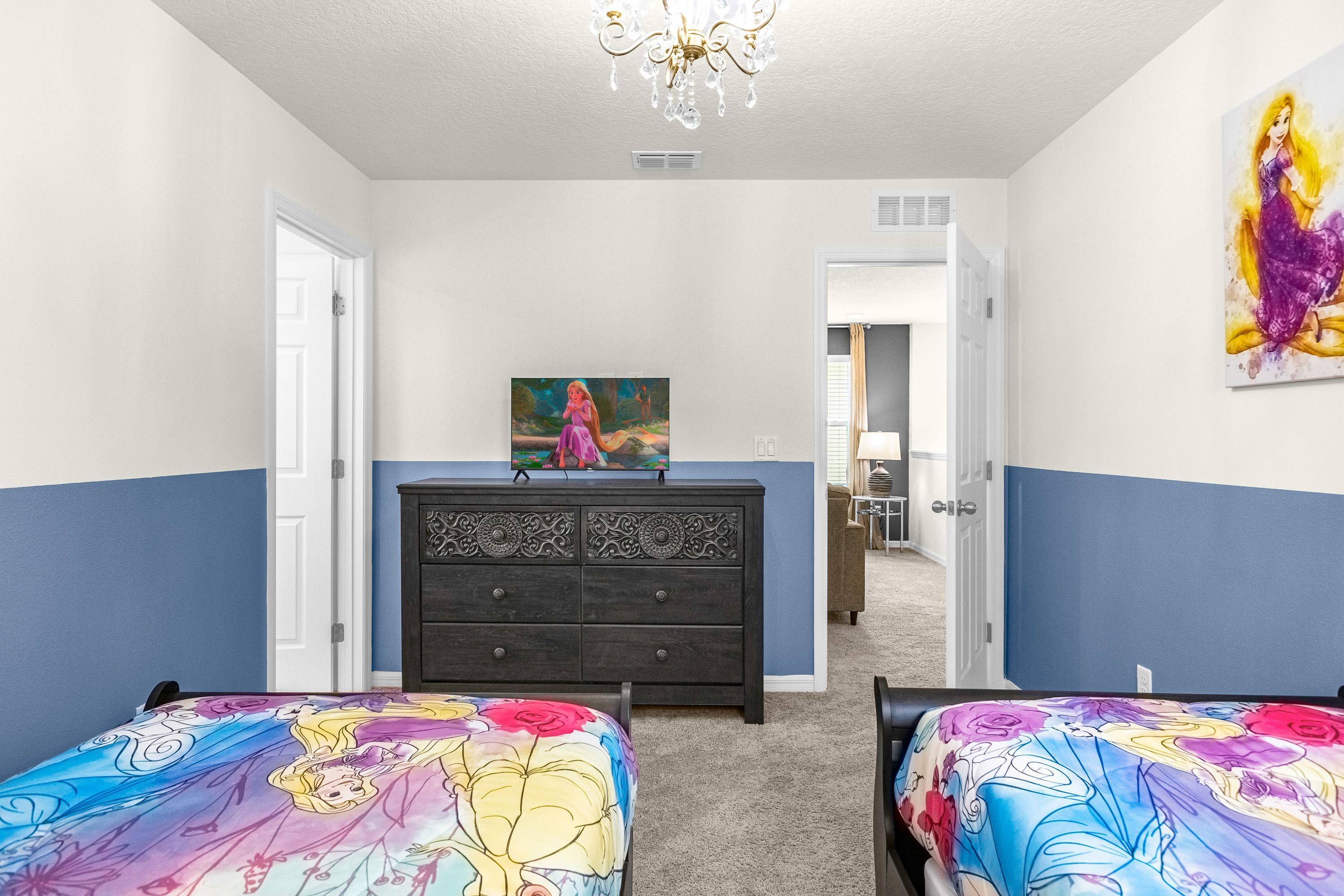 A bedroom with two beds, a dresser, a chandelier, and a painting on the wall.