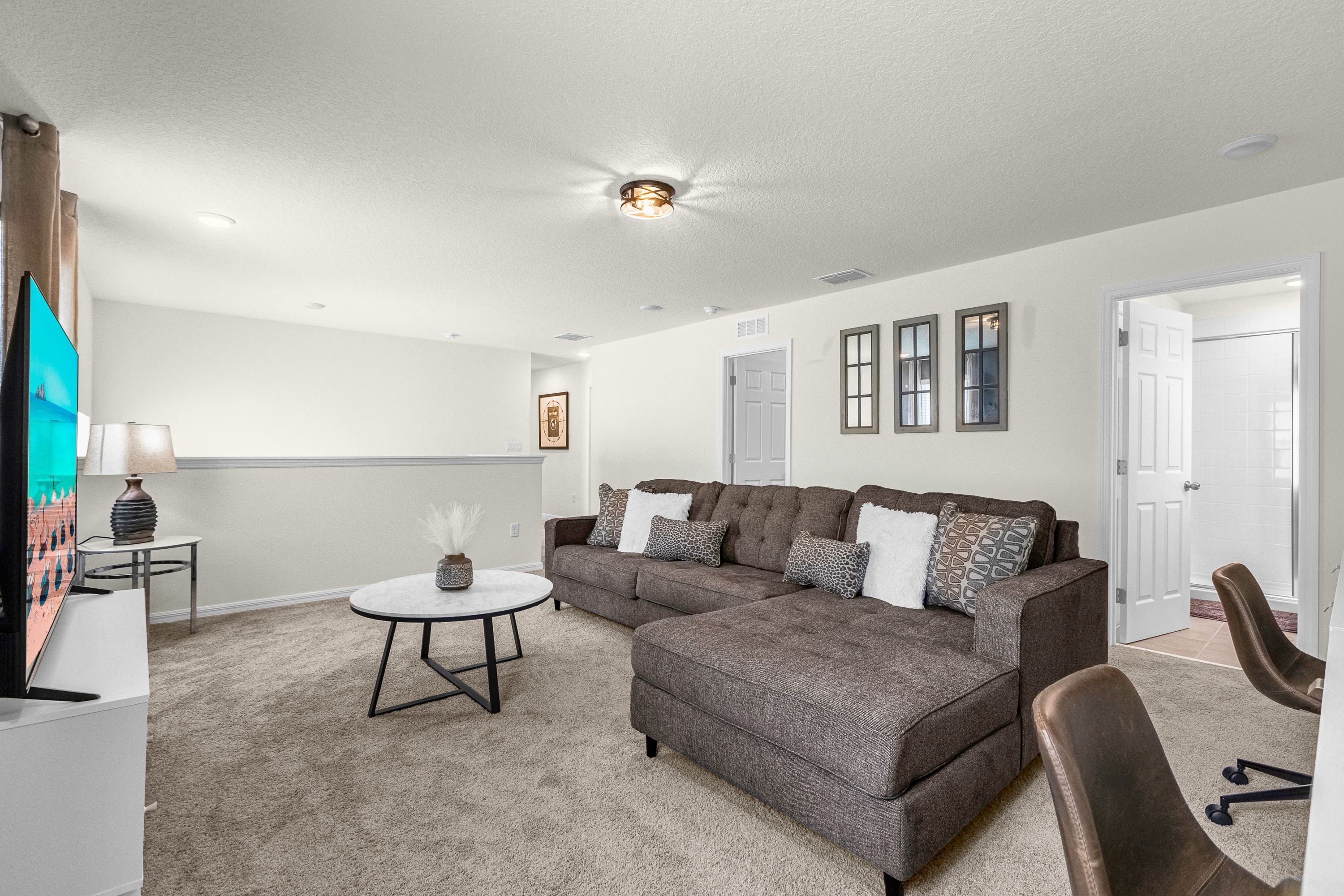 A modern living room with a sectional sofa, a round coffee table, and a flat-screen TV.