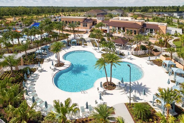 A resort with a large central pool, palm trees, and a variety of buildings.