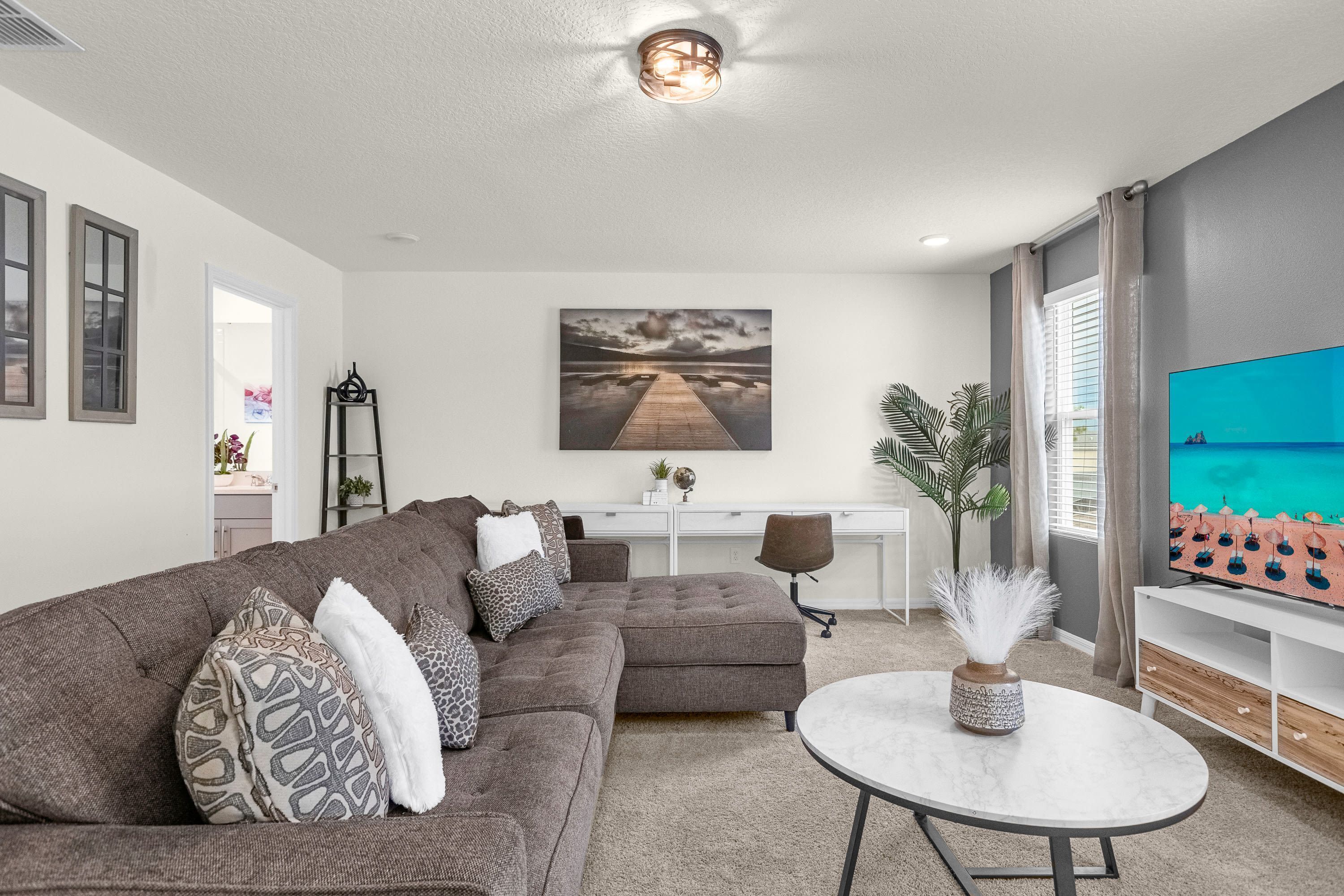 A modern living room with a sectional sofa, a round coffee table, and a flat-screen TV.