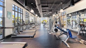 Ein Fitnessstudio mit Laufbändern, Krafttrainingsgeräten und Kurzhanteln.