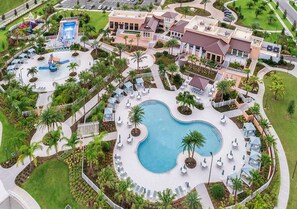 An aerial view of a resort with a central pool, lounge areas, and a water park.