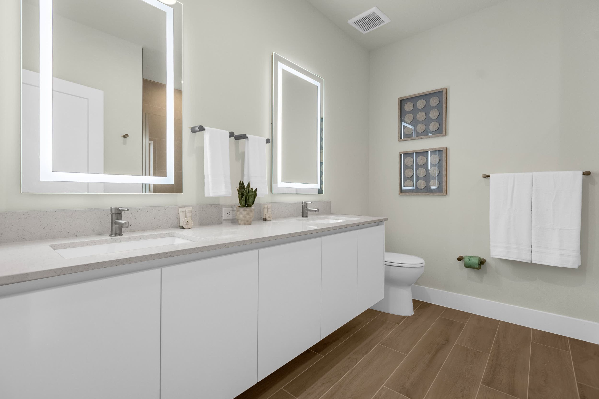 Une salle de bain moderne avec deux lavabos, des toilettes et un grand miroir.